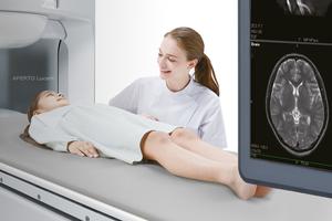 a female healthcare professional smiling at a young girl lying on an MRI machine