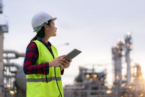 Asian woman petrochemical engineer working with digital tablet Inside oil and gas refinery plant industry factory for inspector safety quality control