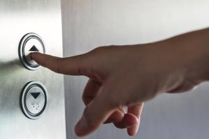 Hand pressing a button of elevator inside the building for upper high level floor, close up shot and focus on button