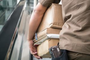 Postman carrying parcels in his hand to deliver them to the customer